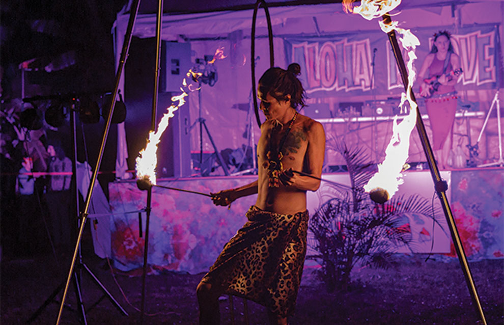 poi artist twirls and performs against a purple lit background.