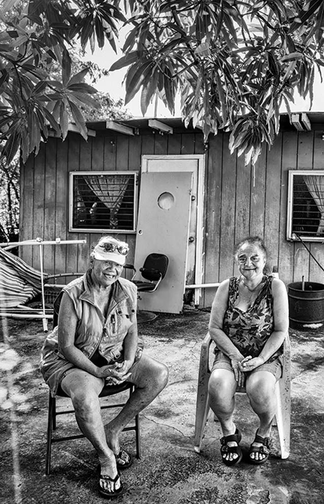 two women sitting on chairs outside a house